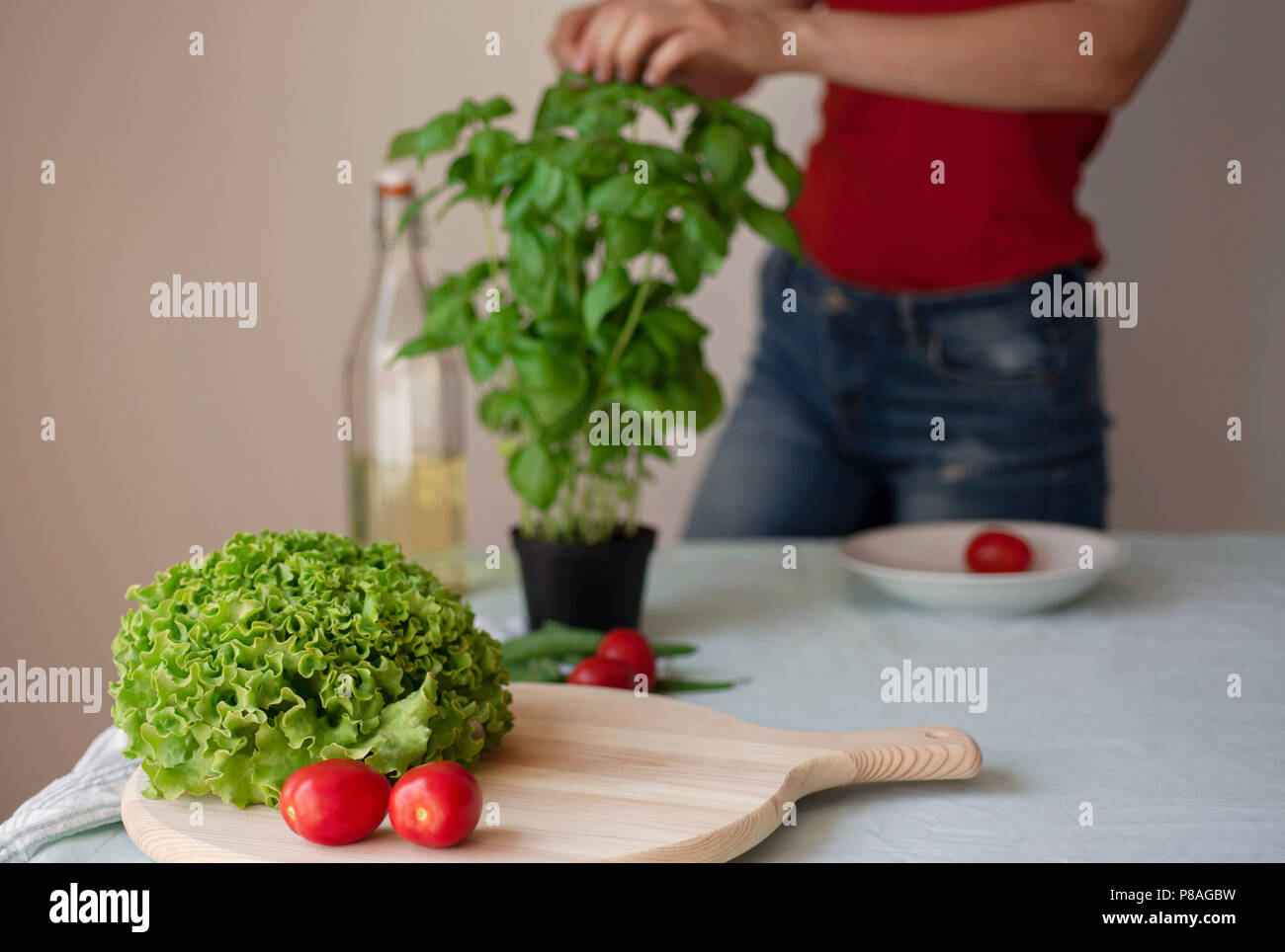 Jeune femme portant des jeans la cuisson des aliments detox végétarien sain. Les ingrédients et la préparation de nourriture italienne sain Banque D'Images