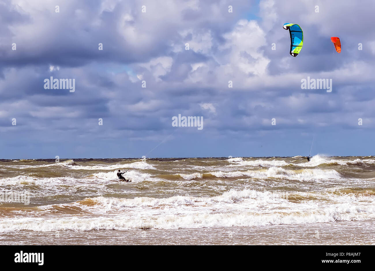 Deux kitesurfers sont les vagues de la mer Baltique près de Venspils beach sous le ciel nuageux. In la mer. Sport extrême le kitesurf. Banque D'Images