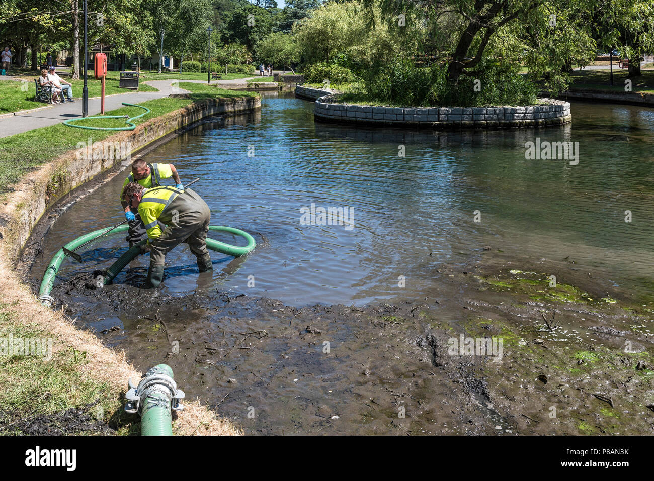 Les travailleurs utilisant une pompe d'aspiration pour enlever la boue et la vase dans un lac. Banque D'Images