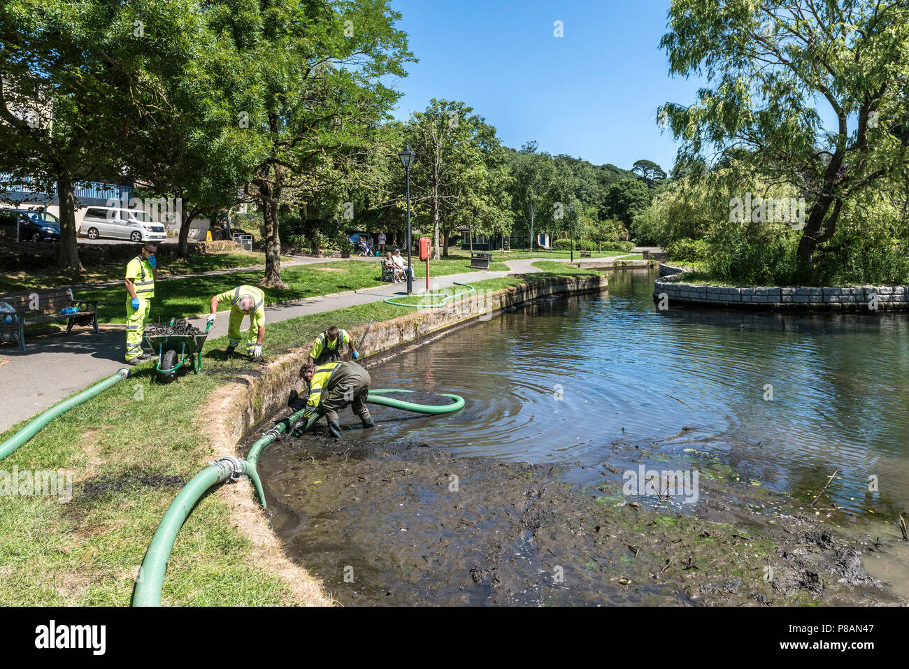 Les travailleurs utilisant une pompe d'aspiration pour enlever la boue et la vase dans un lac. Banque D'Images