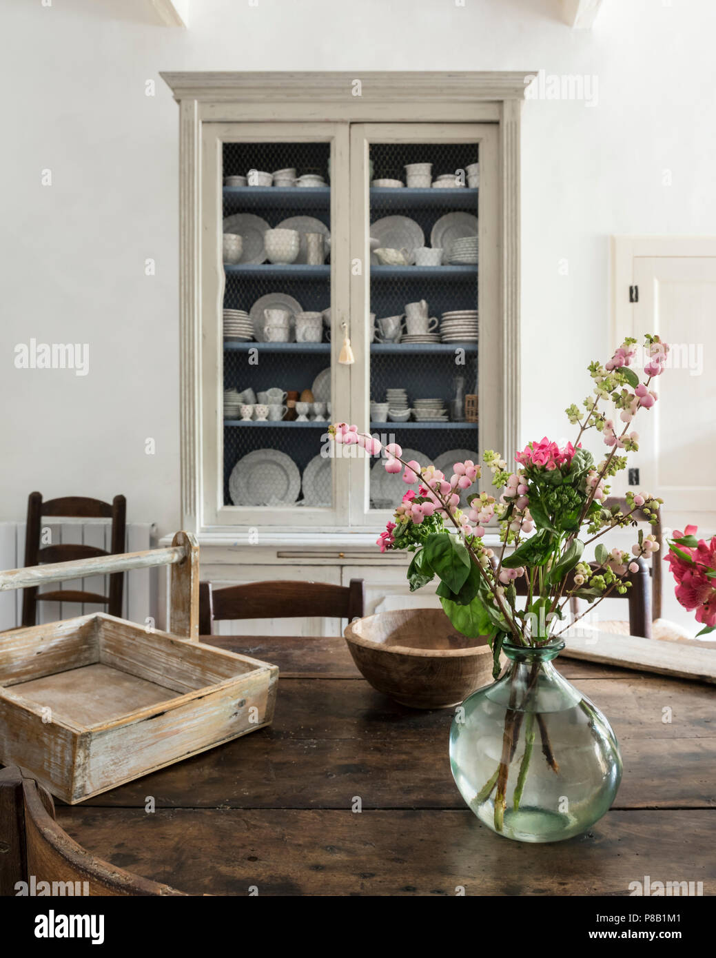 Fleurs roses sur table xixe avec display cabinet d'assiettes et tasses Banque D'Images