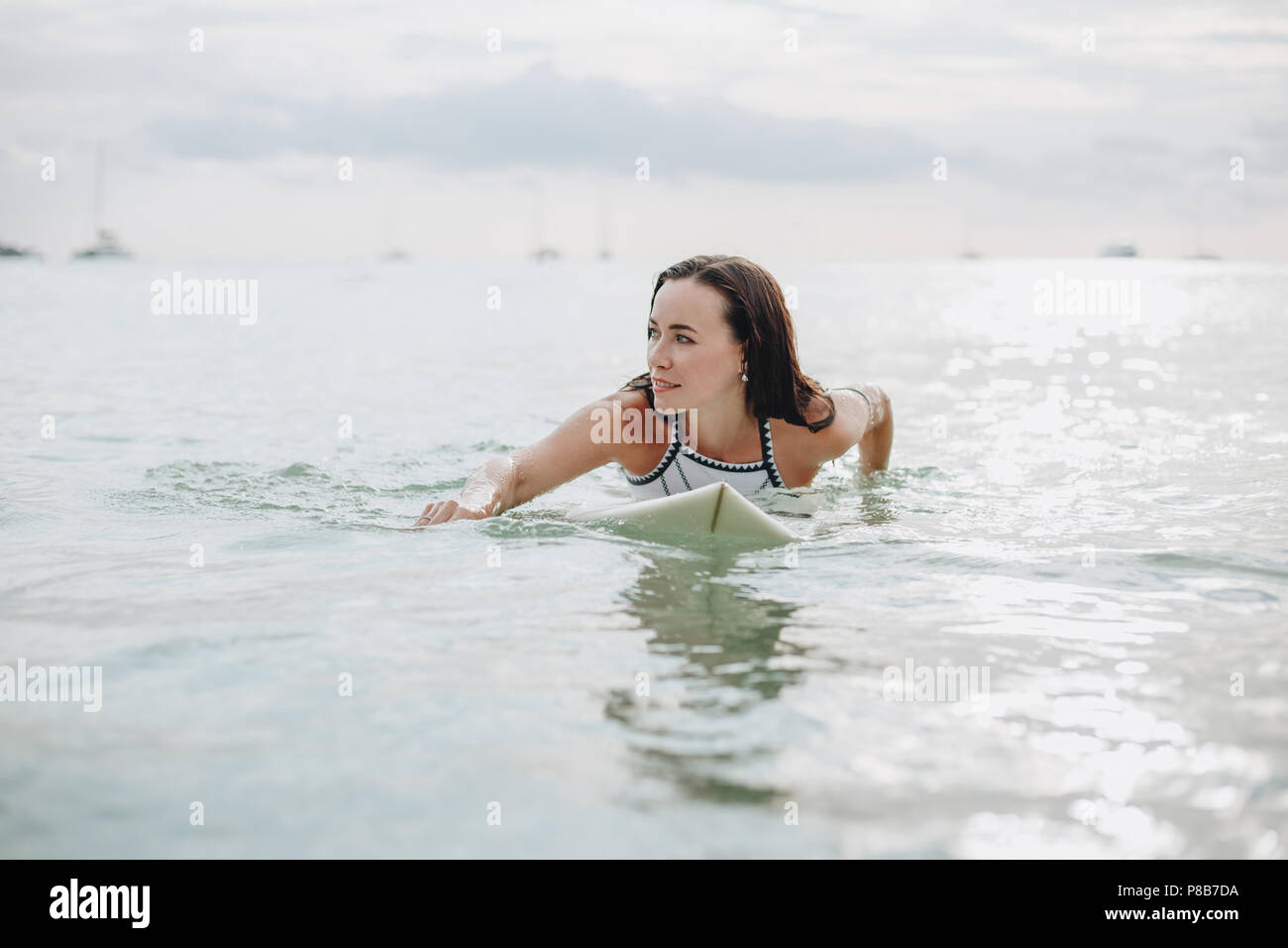 Une belle fille sur une planche de surf dans l'eau Banque D'Images