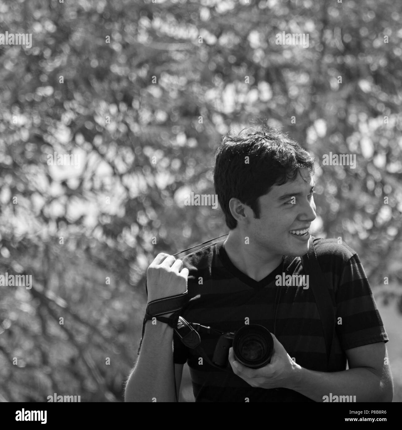 Le jeune photographe outdoor, souriant et tenant une caméra. Banque D'Images