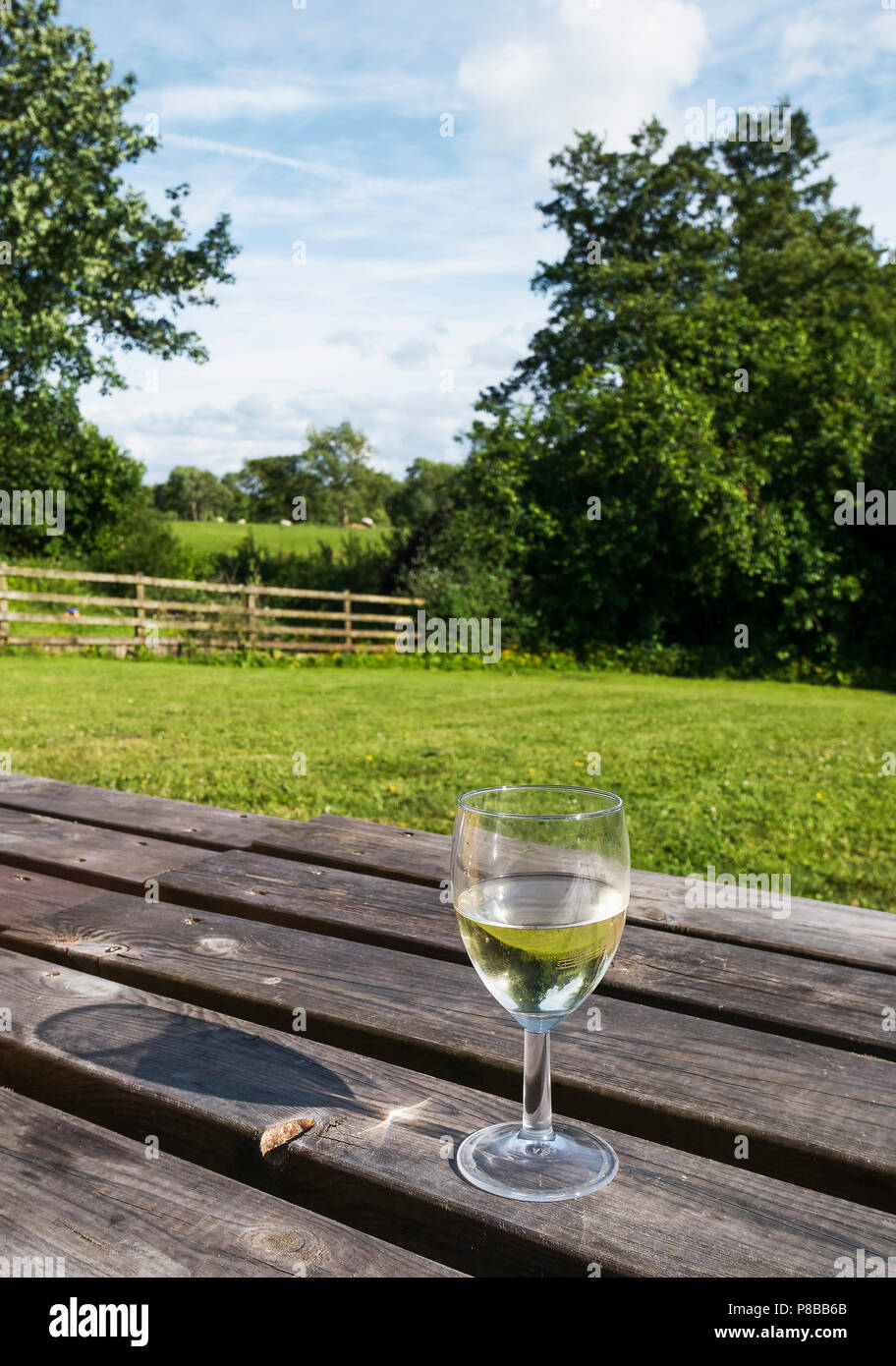 Scène rurale anglaise,Yorkshire, avec un verre de vin sur une table en bois et d'ombre de la fonte de verre par un coucher de soleil. Banque D'Images