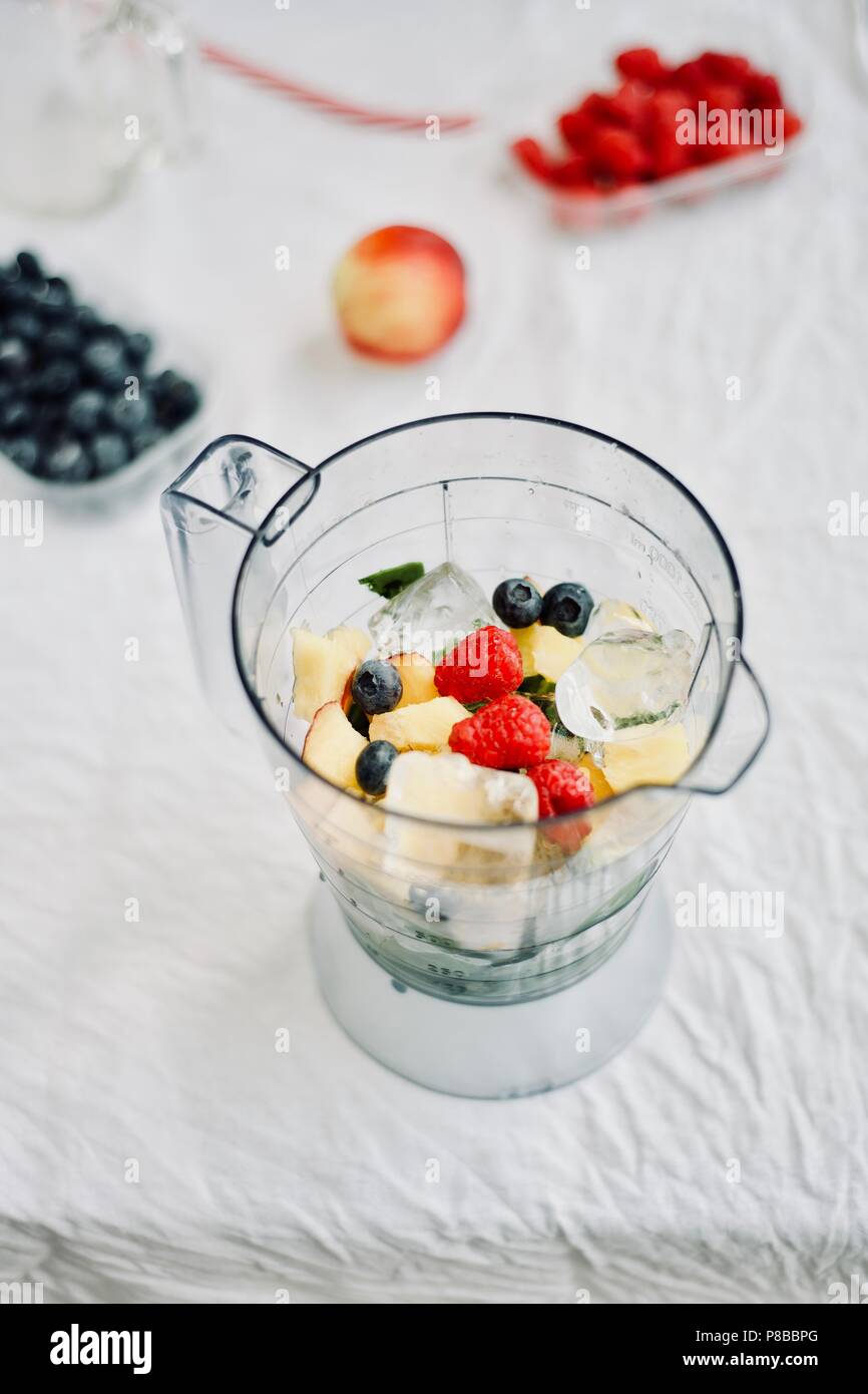 Télévision à jeter d'un mélangeur et petits fruits frais de saison et de fruits sur fond blanc, la cuisson la préparation des smoothies, Detox, saine alimentation propre Banque D'Images