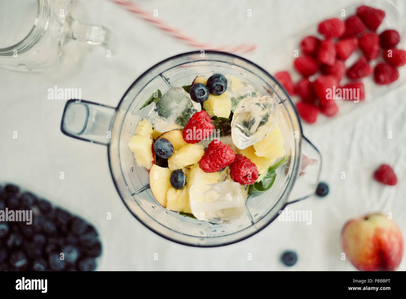 Télévision à jeter d'un mélangeur et petits fruits frais de saison et de fruits sur fond blanc, la cuisson la préparation des smoothies, Detox, saine alimentation propre Banque D'Images