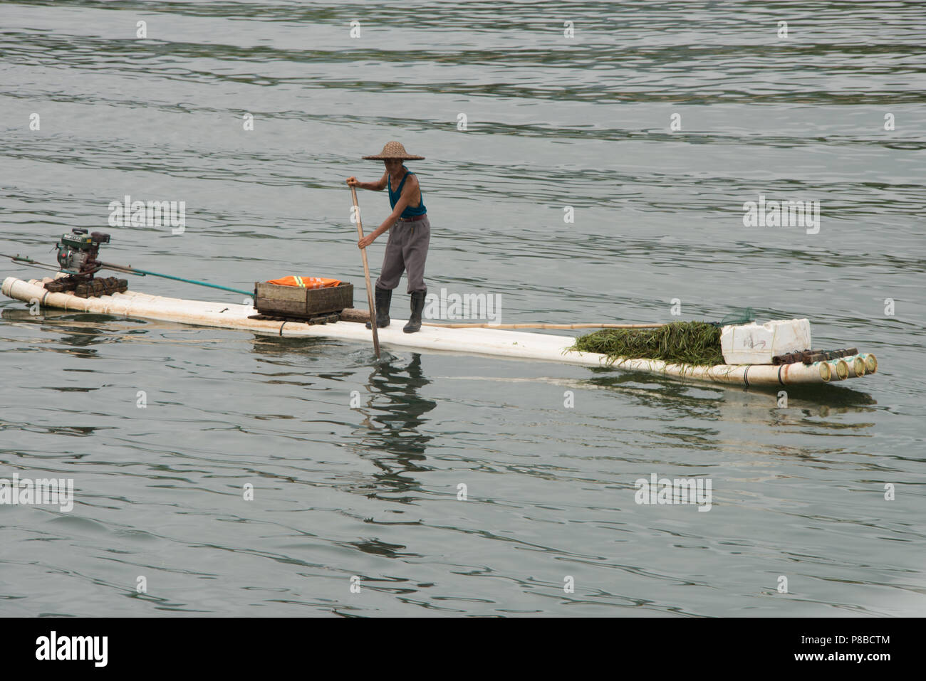 Un pêcheur local sur un raftstyle bateau sur la rivière Li Zhuang du Guangxi en Chine, sur la route de Guilin à Yangshuo. Banque D'Images Un pêcheur local sur un raftstyle bateau sur la rivière Li Zhuang du Guangxi en Chine, sur la route de Guilin à Yangshuo. Banque D'Images
