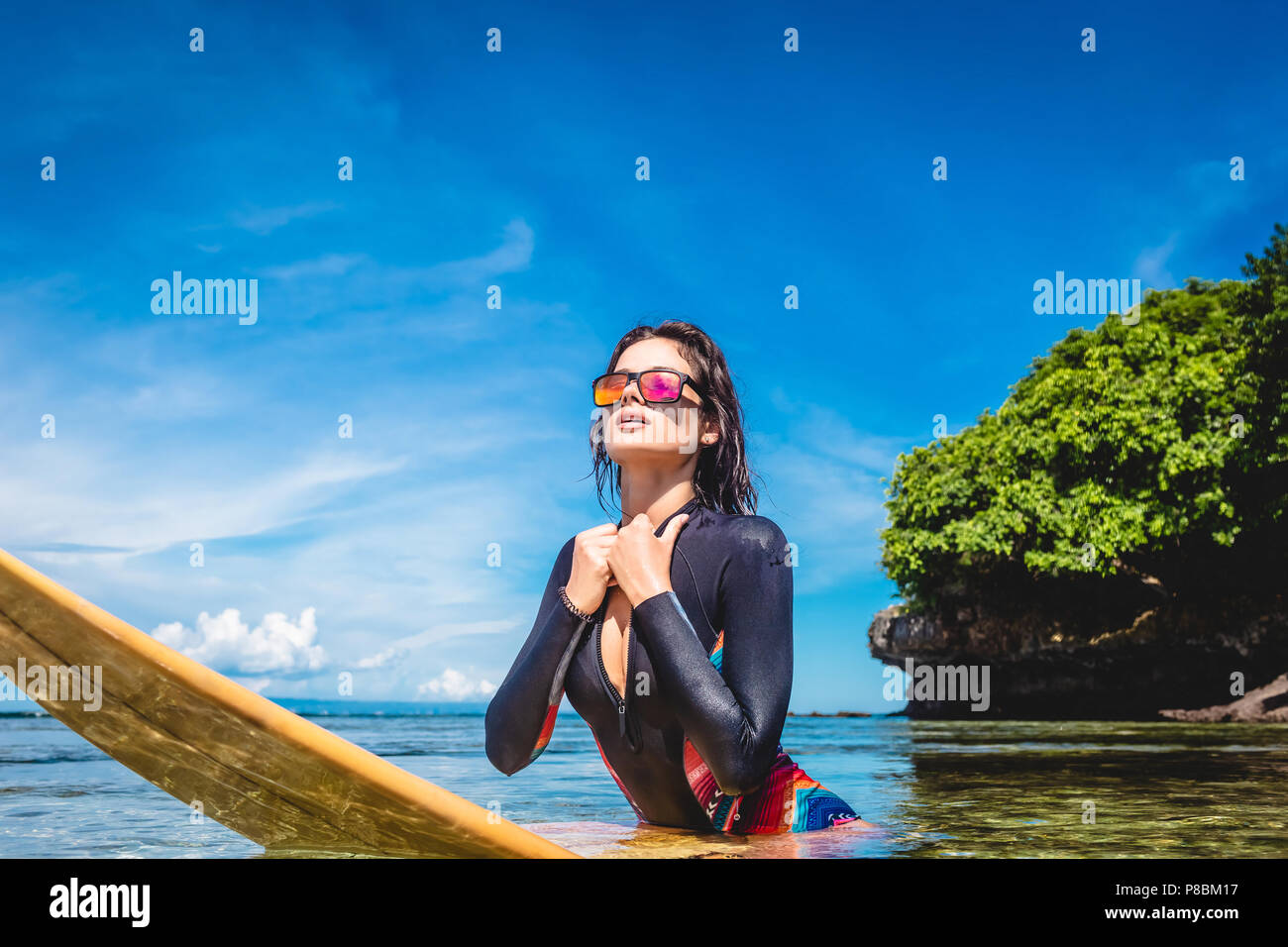 Grande sportive en combinaison et lunettes de soleil sur le surf de l'océan  en bord de plage de Nusa Dua, Bali, Indonésie Photo Stock - Alamy