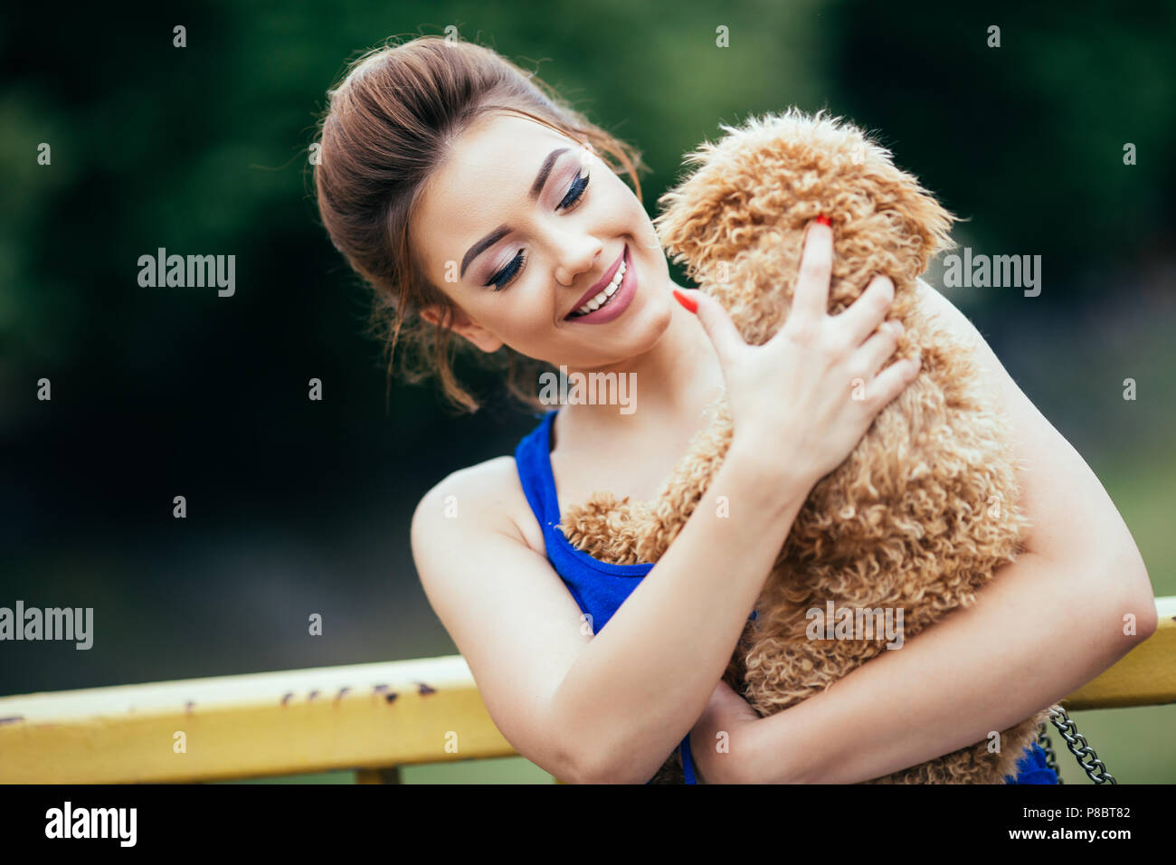 Portrait de la belle jeune femme avec son petit chiot caniche rouge. Banque D'Images
