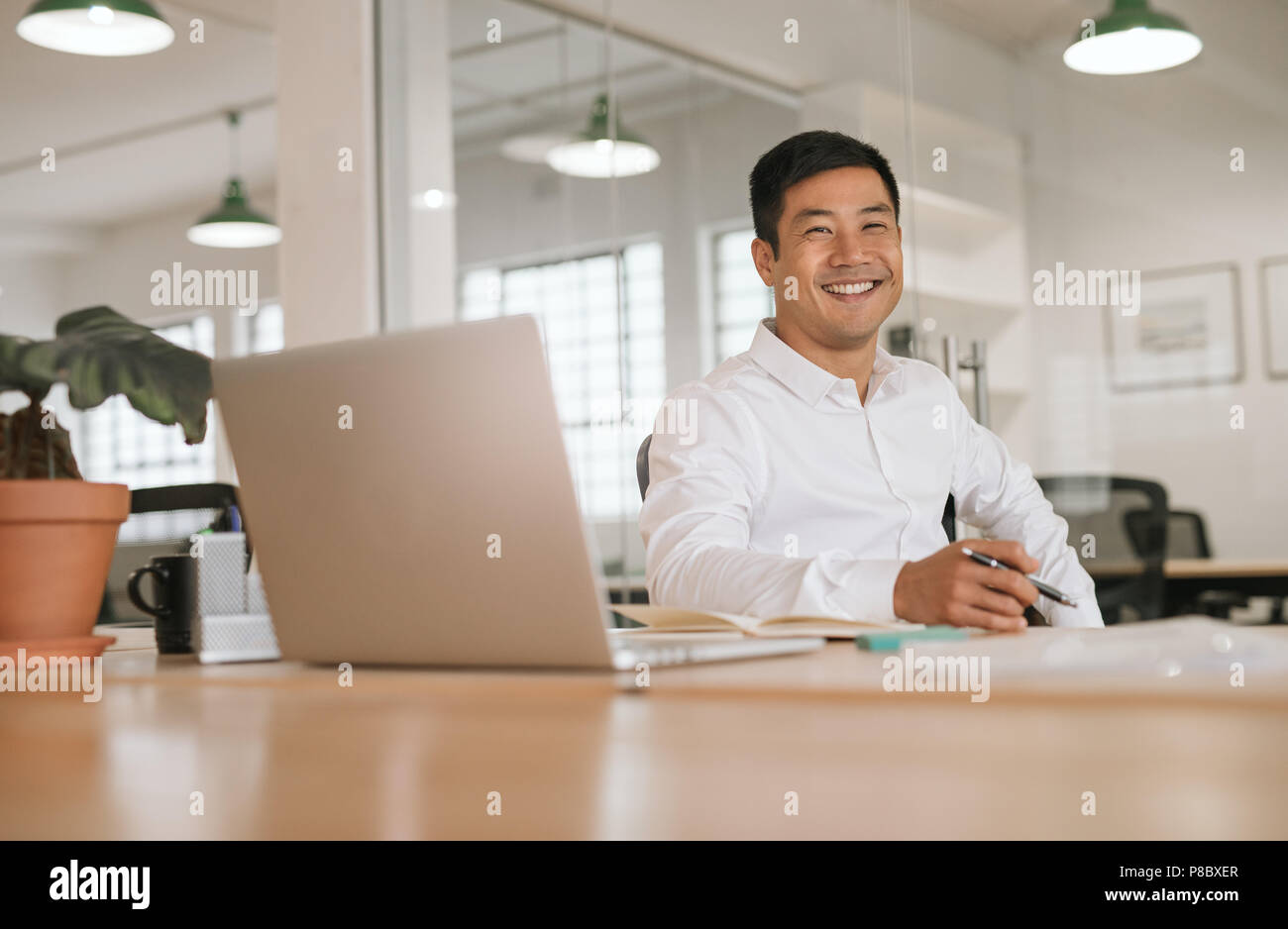 Smiling Young Asian businessman travaillant seul à son bureau 24 Banque D'Images