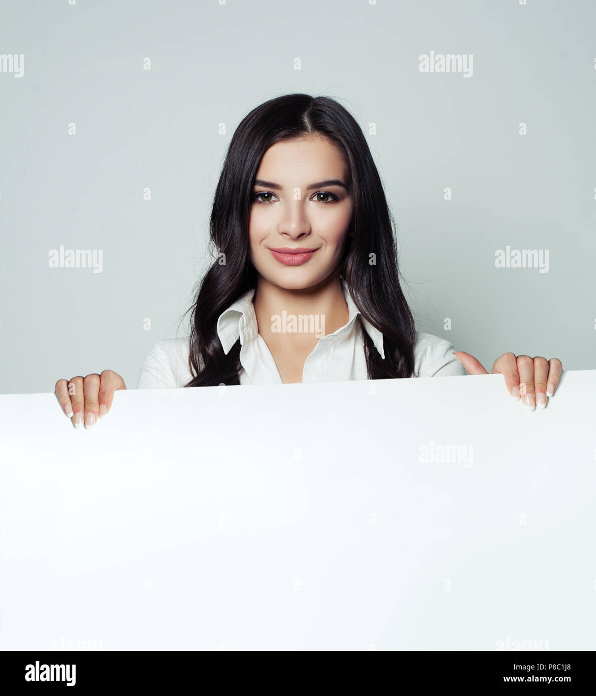 Jeune femme souriante avec arrière-plan de papier blanc vide Banque D'Images