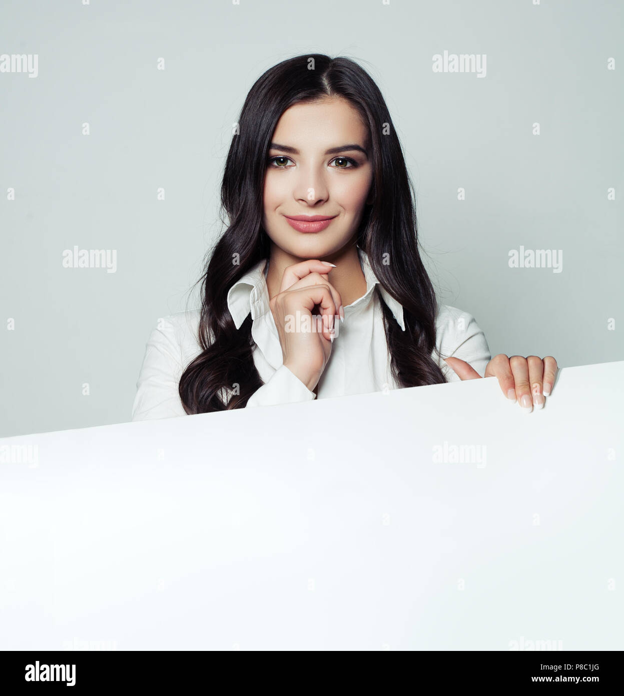 Cheerful woman holding vide blanc papier blanc arrière-plan et looking at camera Banque D'Images