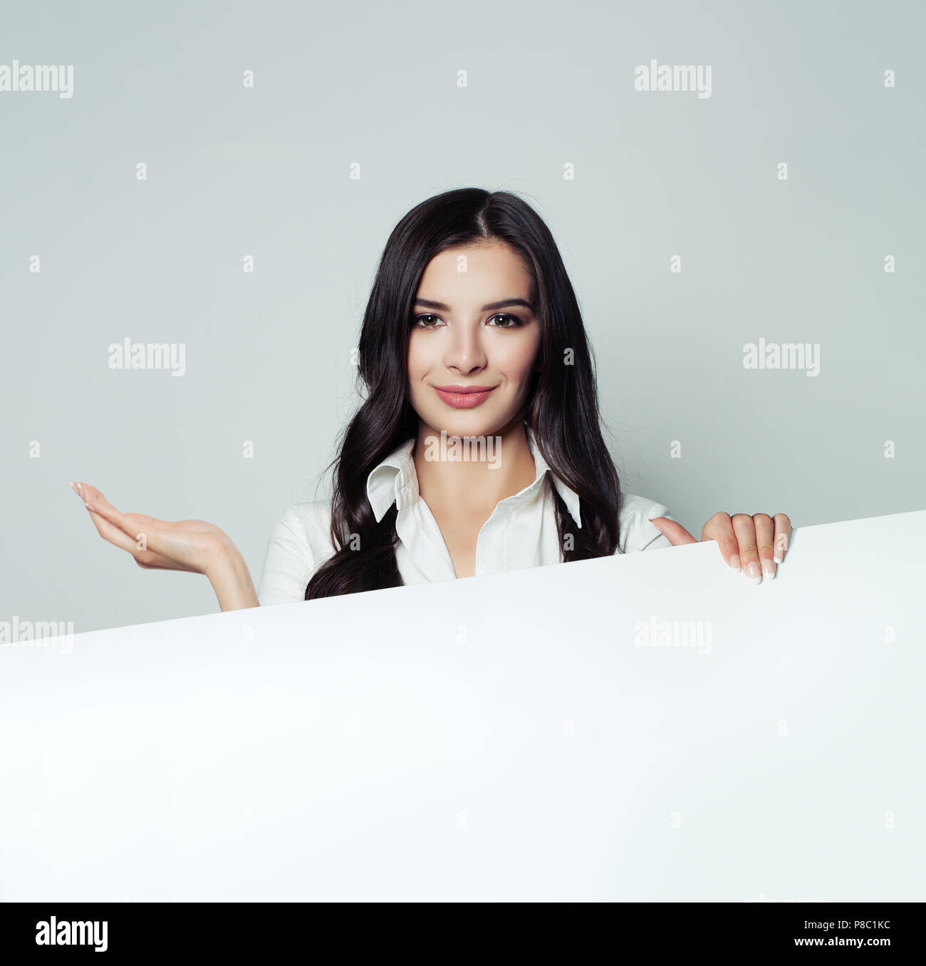 Business Woman holding white papier vierge bannière et montrant la main vide. Jeune femme souriante. Le placement de produit, l'infographie et presentati Banque D'Images