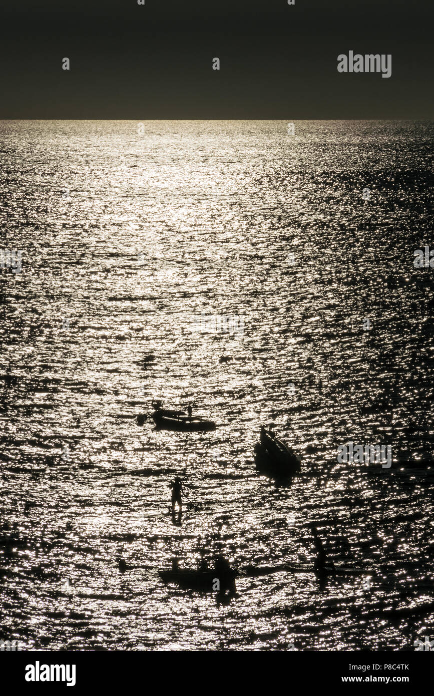 PUERTO VALLARTA, MEXIQUE - Mars 10, 2018 : les personnes non identifiables en silhouette, sur paddle boards entre de petits bateaux de pêche comme lors d'un coucher de soleil sur le Paci Banque D'Images