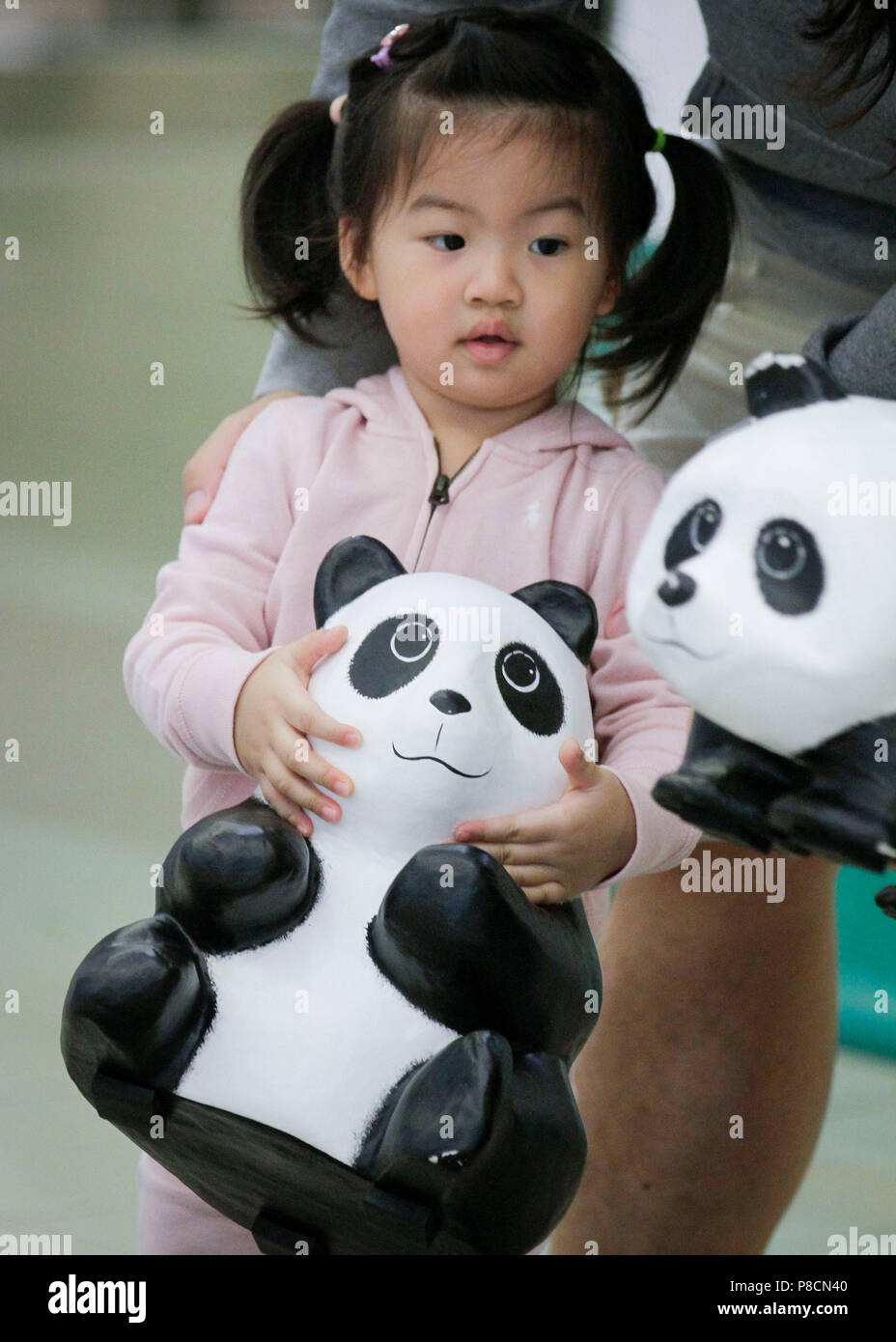 Vancouver, Canada. 10 juillet, 2018. Une fille joue avec un papier-mâché panda lors d'une exposition de l'art 'papier mâché 1 600 pandas' at Metrotown Mall à Vancouver, Canada, le 10 juillet 2018. '1 600 pandas', une oeuvre papier mâché créé en 2008 par l'artiste français Paulo Grangeon pour le Fonds mondial pour la nature (WWF), a commencé sa tournée de l'exposition du Canada mardi. Credit : Liang sen/Xinhua/Alamy Live News Banque D'Images