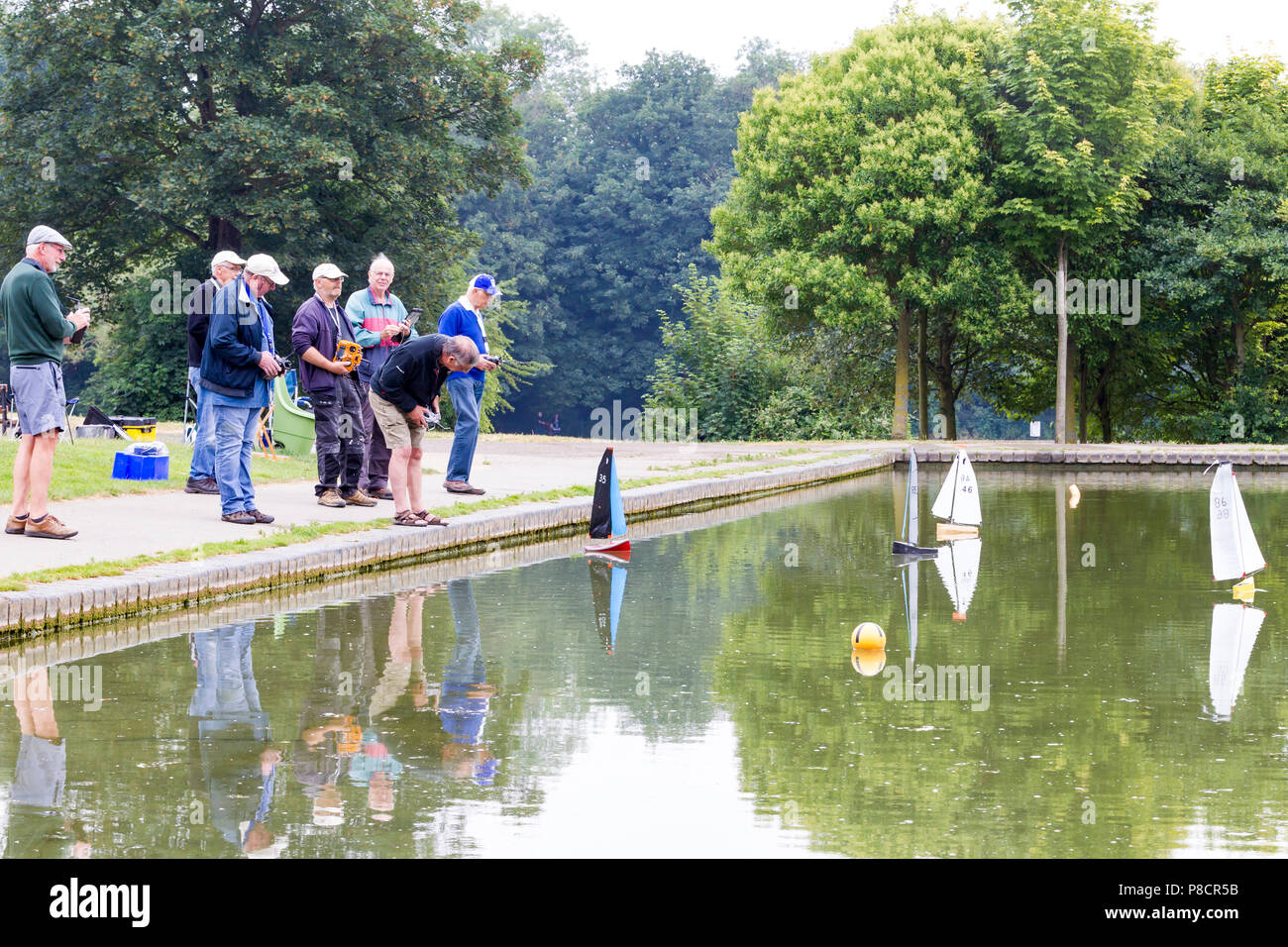 Northampton. Royaume-uni 11 juillet 2018. Météo. Les personnes bénéficiant de l'air du refroidisseur matin leur voile Yachts classe Footy sur le lac de plaisance dans la région de Abington Park ce matin, ciel nuageux et une légère brise chaude du secours donnant le temps récent. Credit : Keith J Smith./Alamy Live News Banque D'Images