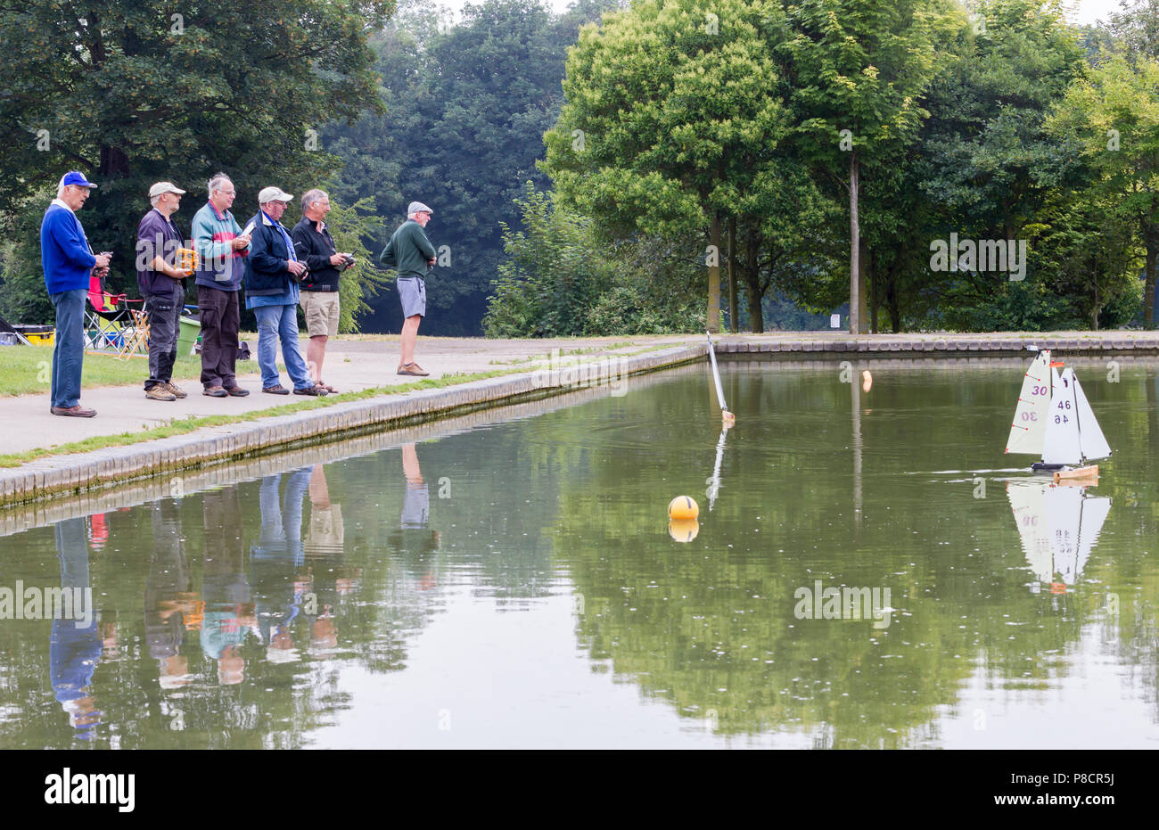 Northampton. Royaume-uni 11 juillet 2018. Météo. Les personnes bénéficiant de l'air du refroidisseur matin leur voile Yachts classe Footy sur le lac de plaisance dans la région de Abington Park ce matin, ciel nuageux et une légère brise chaude du secours donnant le temps récent. Credit : Keith J Smith./Alamy Live News Banque D'Images