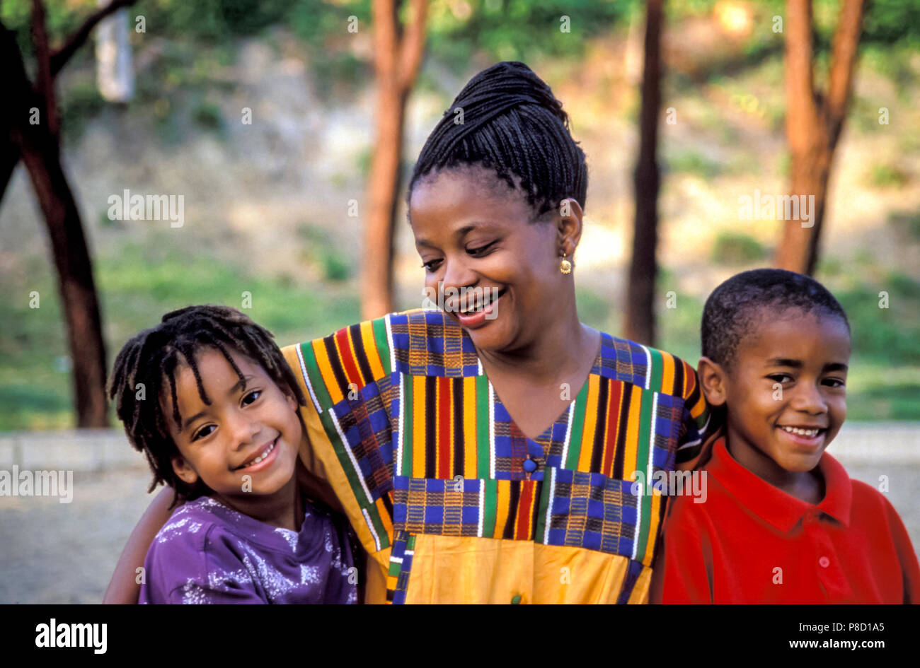 Portrait de maman portant robe couleur ethnique sourit à jumeau fraternel des enfants. M. © Myrleen Pearson Banque D'Images