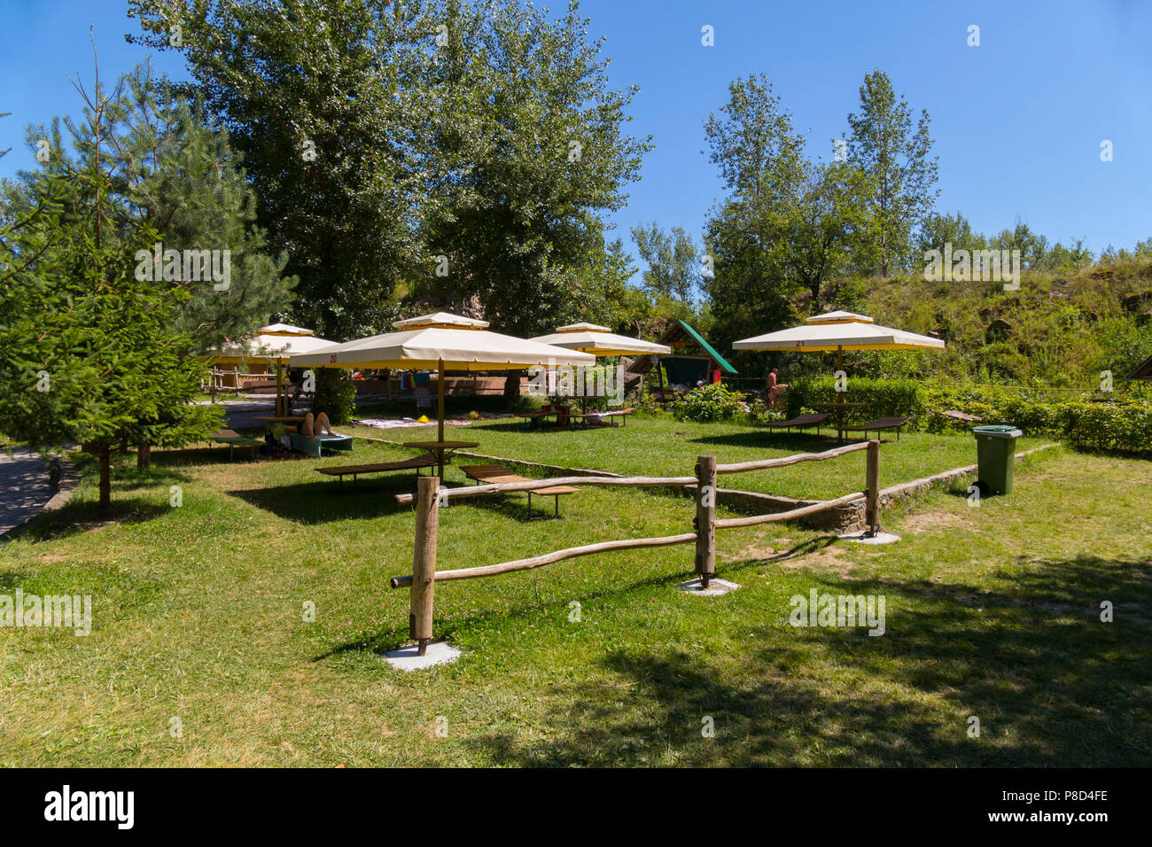 Grands parasols avec transats sous eux dans le contexte d'un beau parc avec une clôture en bois . Pour votre conception Banque D'Images