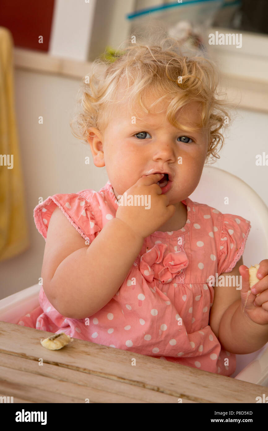 Une fillette d'un an se nourrir une banane Banque D'Images