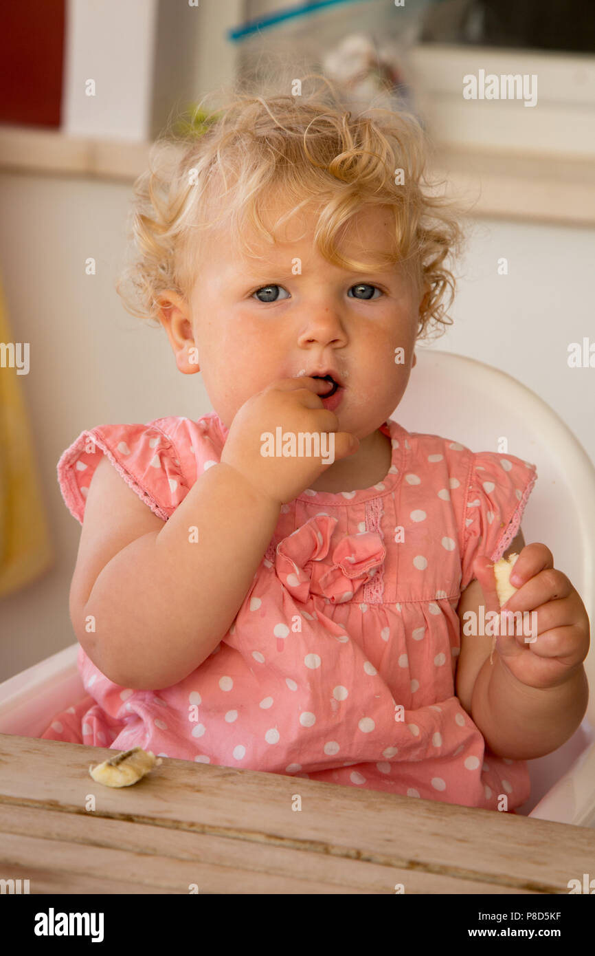 Une fillette d'un an se nourrir une banane Banque D'Images
