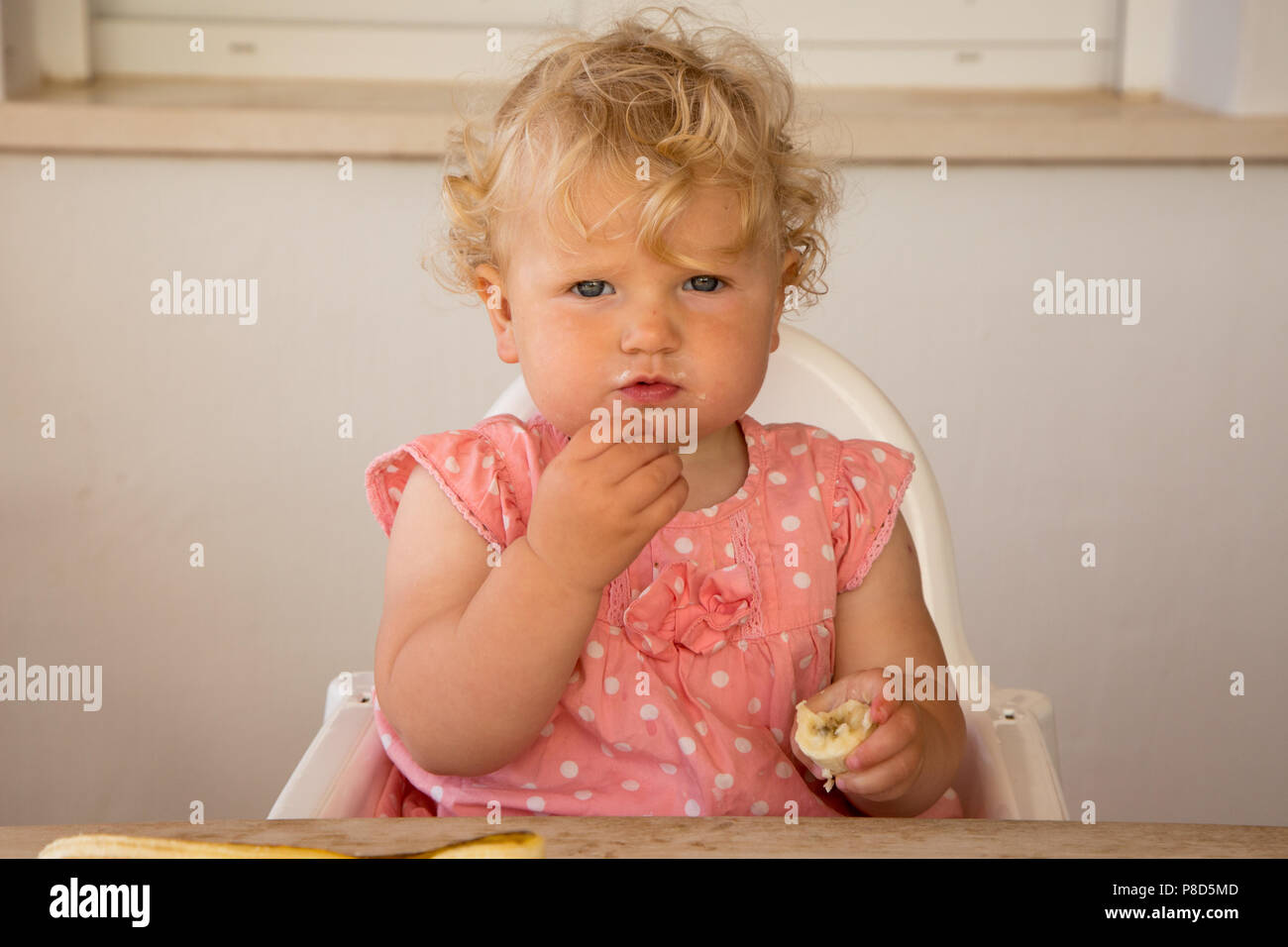 Une fillette d'un an se nourrir une banane Banque D'Images