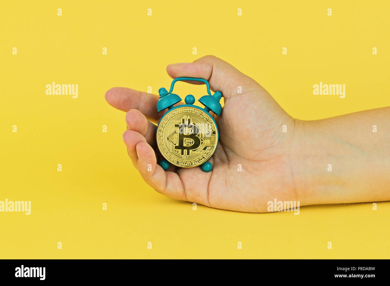 Main courante petit réveil avec bitcoin sur fond jaune. Concept ne signifie pas la croissance de bitcoin. Statistiques de la croissance et de l'automne de cryptocurrency Banque D'Images