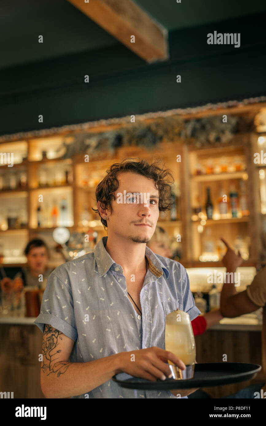 Jeune serveur qui sert des cocktails dans un bar branché Banque D'Images