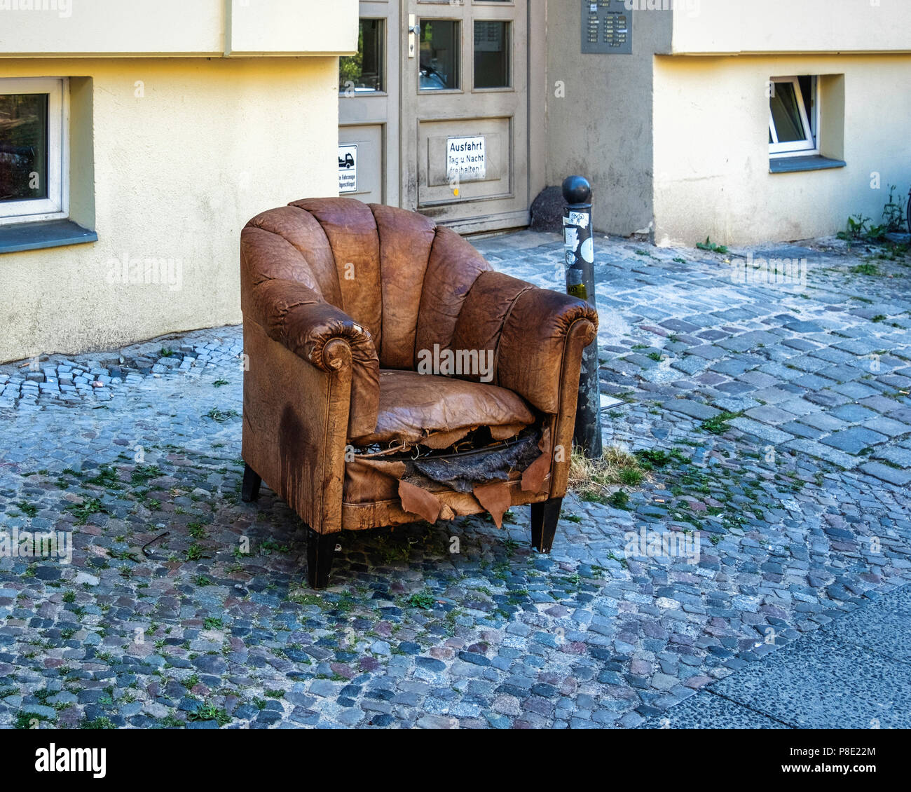 Vieille chaise en cuir jetés sur les trottoirs de la ville. Meubles abandonnés sur la chaussée urbaine Banque D'Images