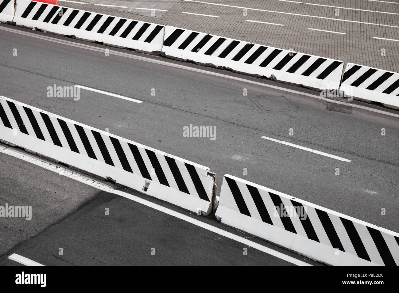 Route asphaltée en béton blanc à rayures blocs frontière Banque D'Images