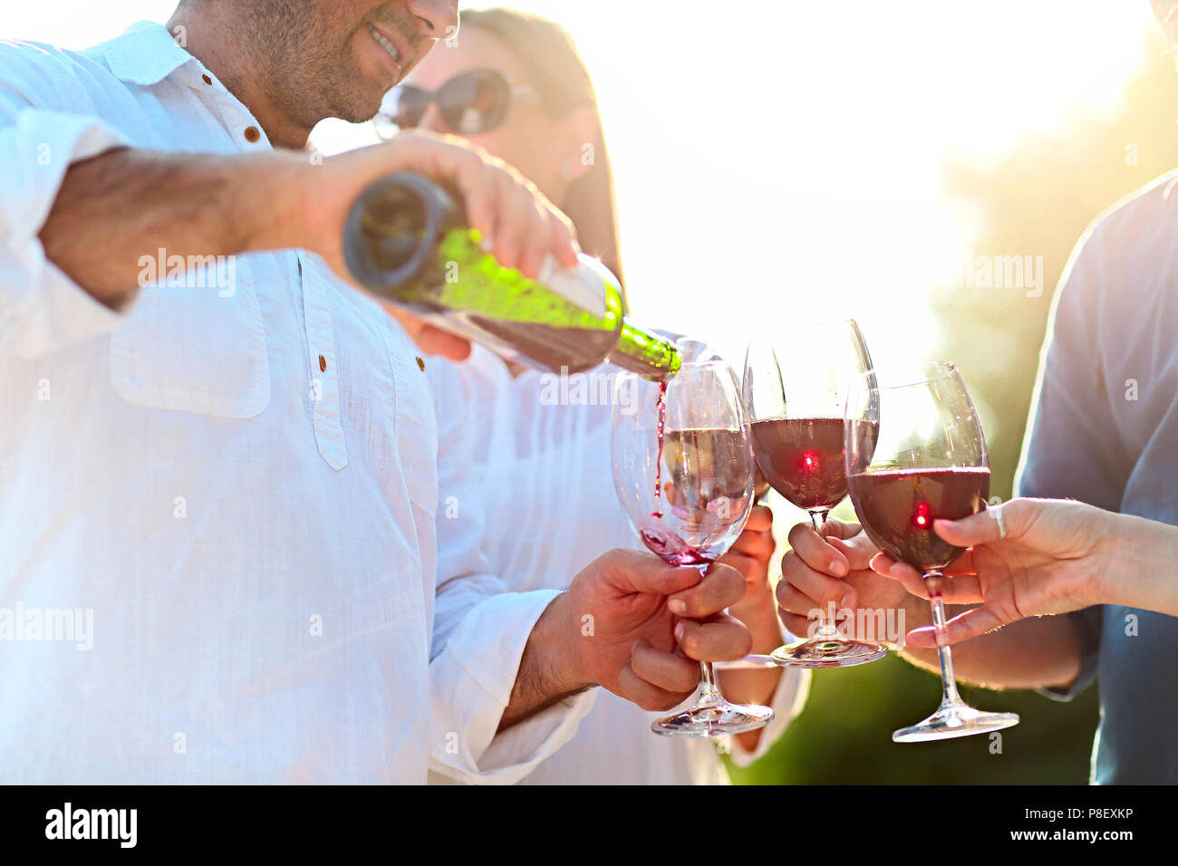 Les gens à l'extérieur du vin partie. Fête du vin. Man pouring red wine in à l'wineglasses Banque D'Images