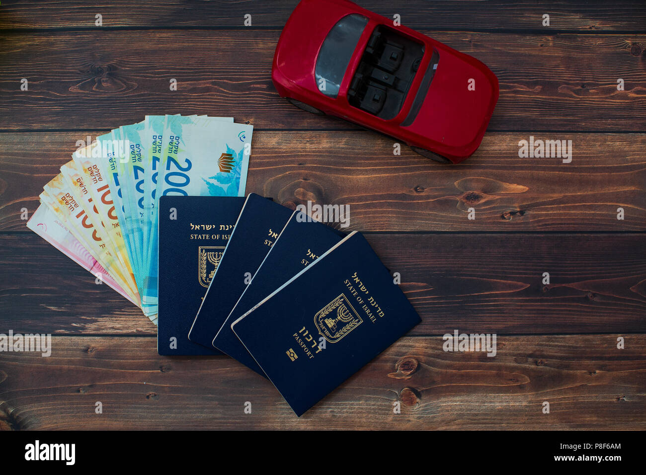 La préparation pour un voyage en Israël, voiture rouge, argent, passeport sur table en bois Banque D'Images