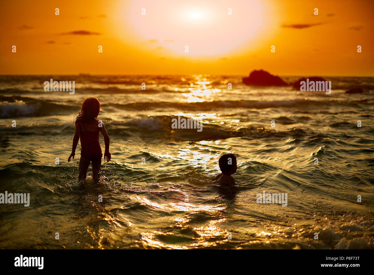 Silhouette d'enfant jouant avec bateau à voile sur sunset beach Banque D'Images