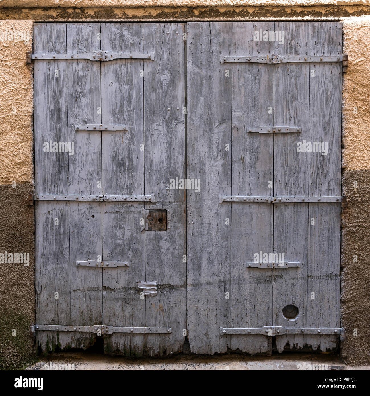 Très old weathered bleu gris portes en ancien mur de la ville médiévale de village en français provence Banque D'Images