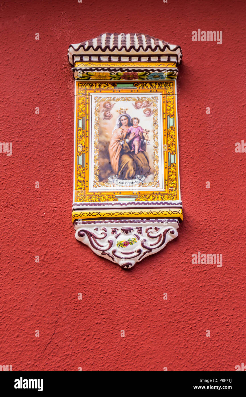 Vierge Marie et l'enfant Jésus peint sur un petit porche en céramique présentent sur un mur de couleur grena sur l'île de Tenerife Banque D'Images