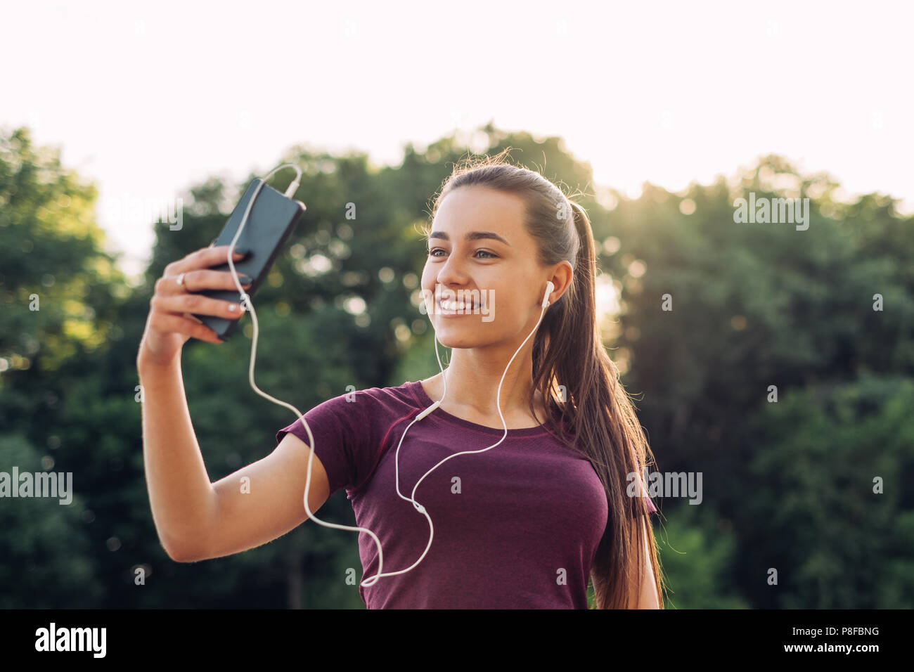 Femme souriante en tenant son téléphone mobile selfies, Minsk, Bélarus Banque D'Images
