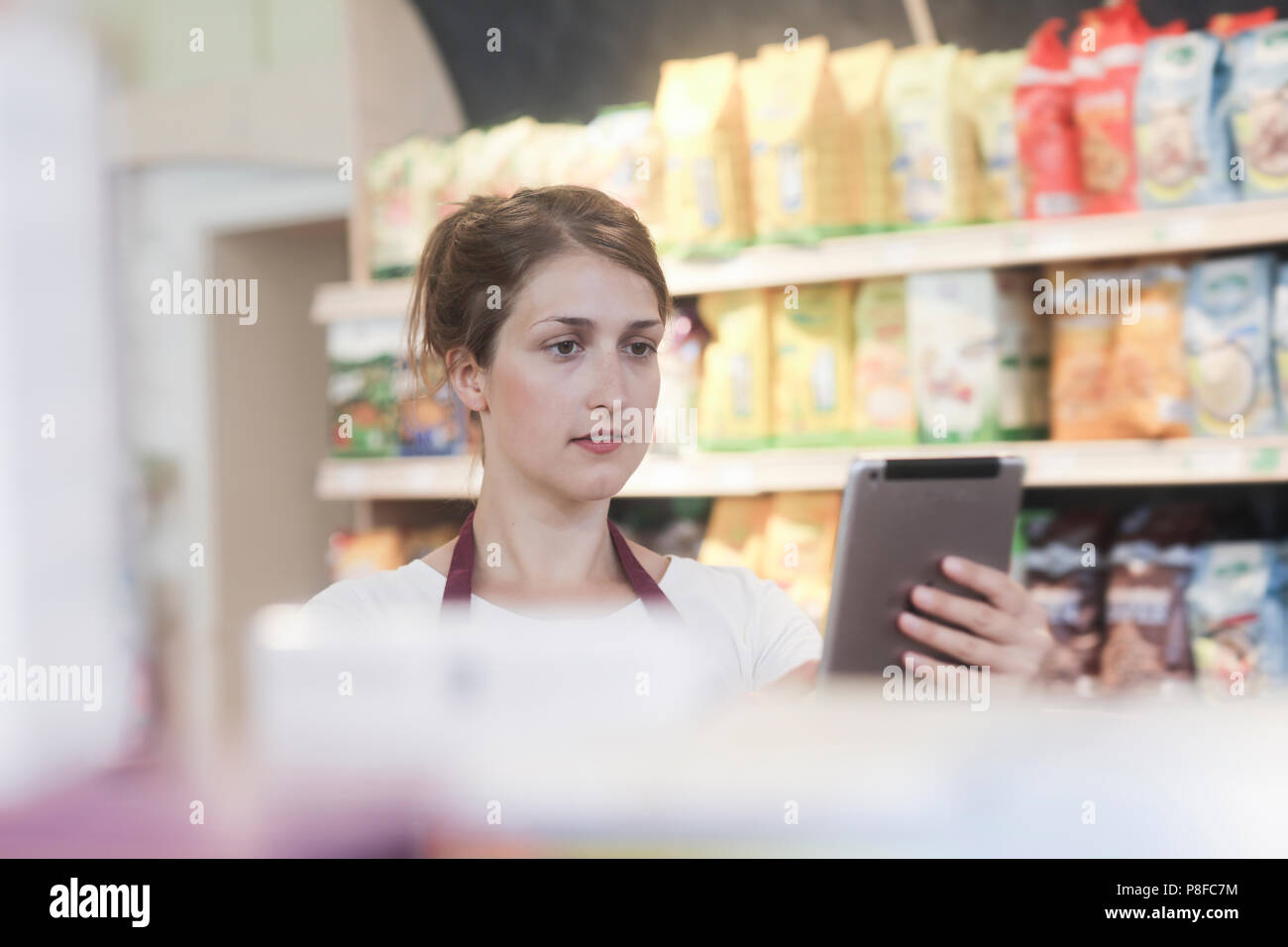 Supermarché shop assistant contrôle de produits en utilisant une tablette numérique Banque D'Images