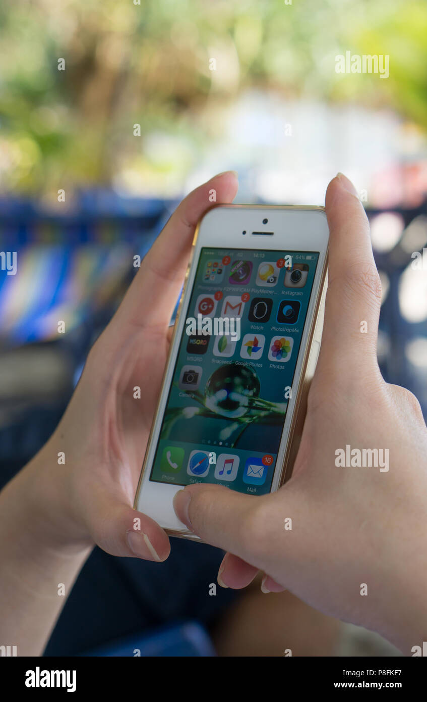 RAYONG, Thaïlande - 12 Avril 2016 : une femme main tenant l'iphone à l'écran d'accueil Banque D'Images