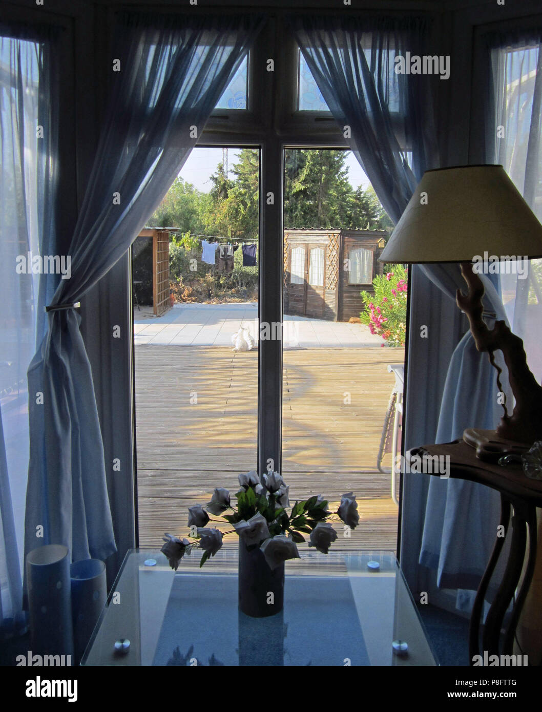 Voir à la fenêtre à travers les rideaux sur un Jardin Ouvert en été dans une maison mobile en Espagne Banque D'Images