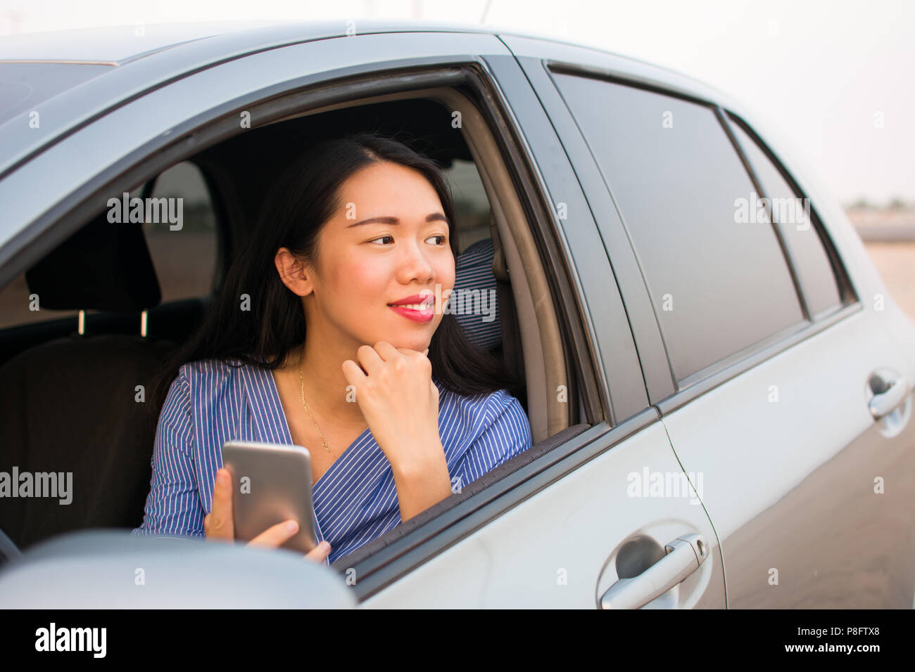 Asian girl à l'aide d'un smart phone in car Banque D'Images