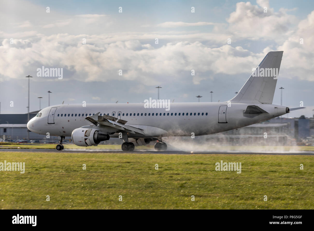 Un Airbus A320 avion de ligne avec la livrée blanche à l'atterrissage sur une piste mouillée avec inversion de poussée et de pulvérisation Banque D'Images