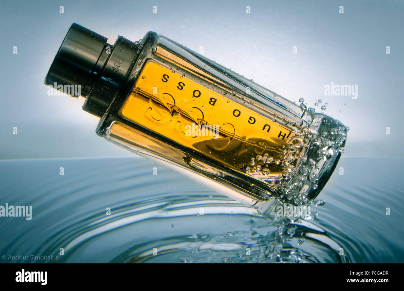 Bouteille de parfum Hugo Boss éclaboussant dans l'eau avec des bulles dynamiques et une réflexion lumineuse élégante, mettant en valeur un parfum de luxe dans la St publicitaire créative Banque D'Images