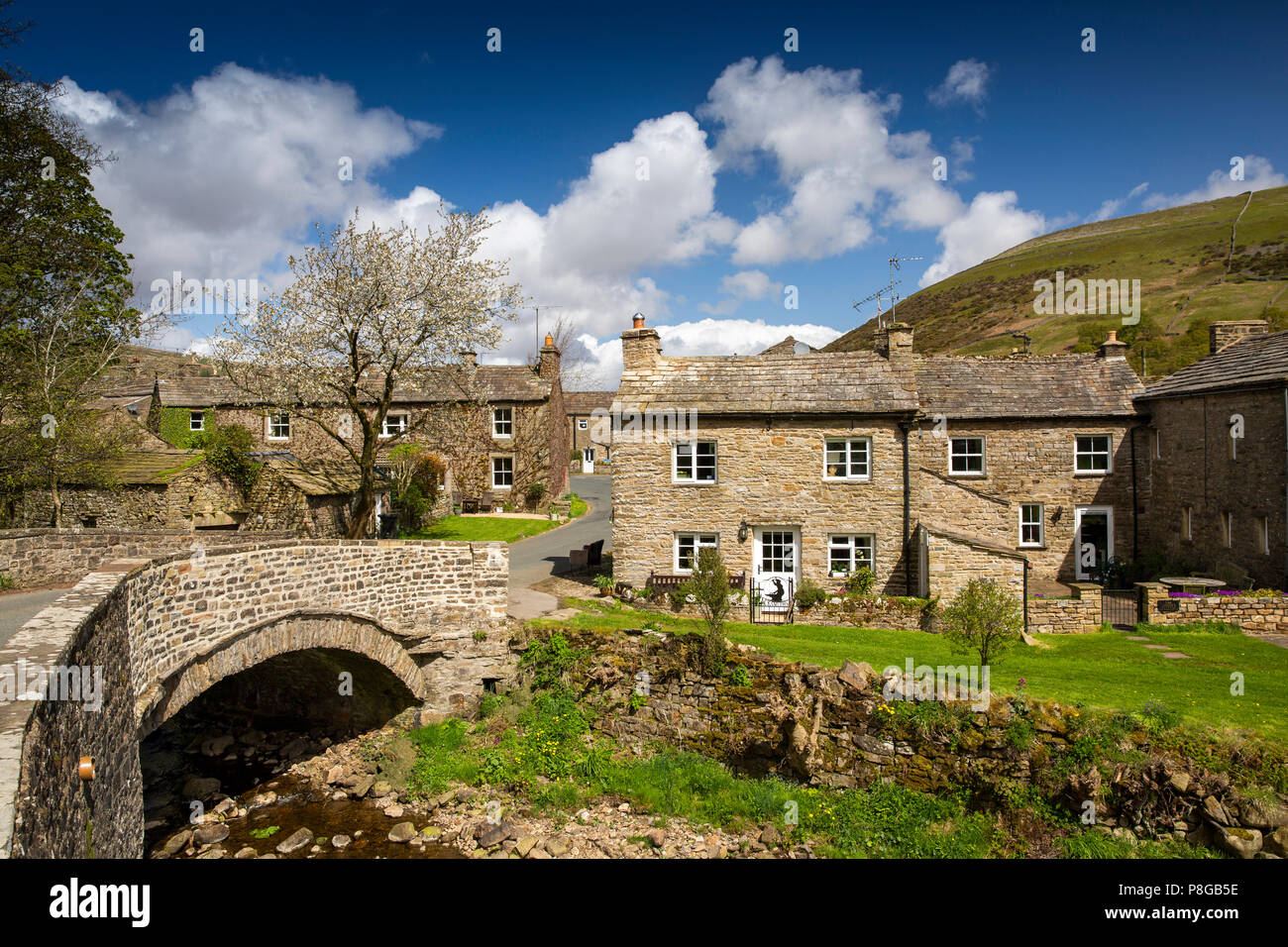 Royaume-uni, Angleterre, dans le Yorkshire, Swaledale, Thwaite, maisons de village à travers pont sur la paille Beck Banque D'Images