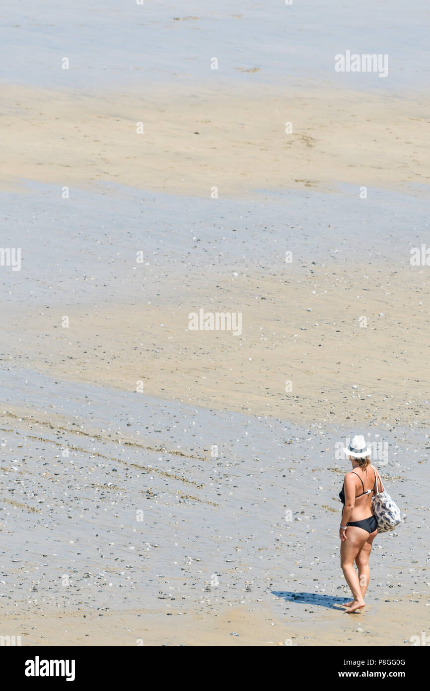 Une femme avec un chapeau et sac d'épaule, et vêtu d'un bikini, les promenades le long de la rive de l'océan Atlantique, il répond à la plage de sable à la place Birmingham Inverness Banque D'Images