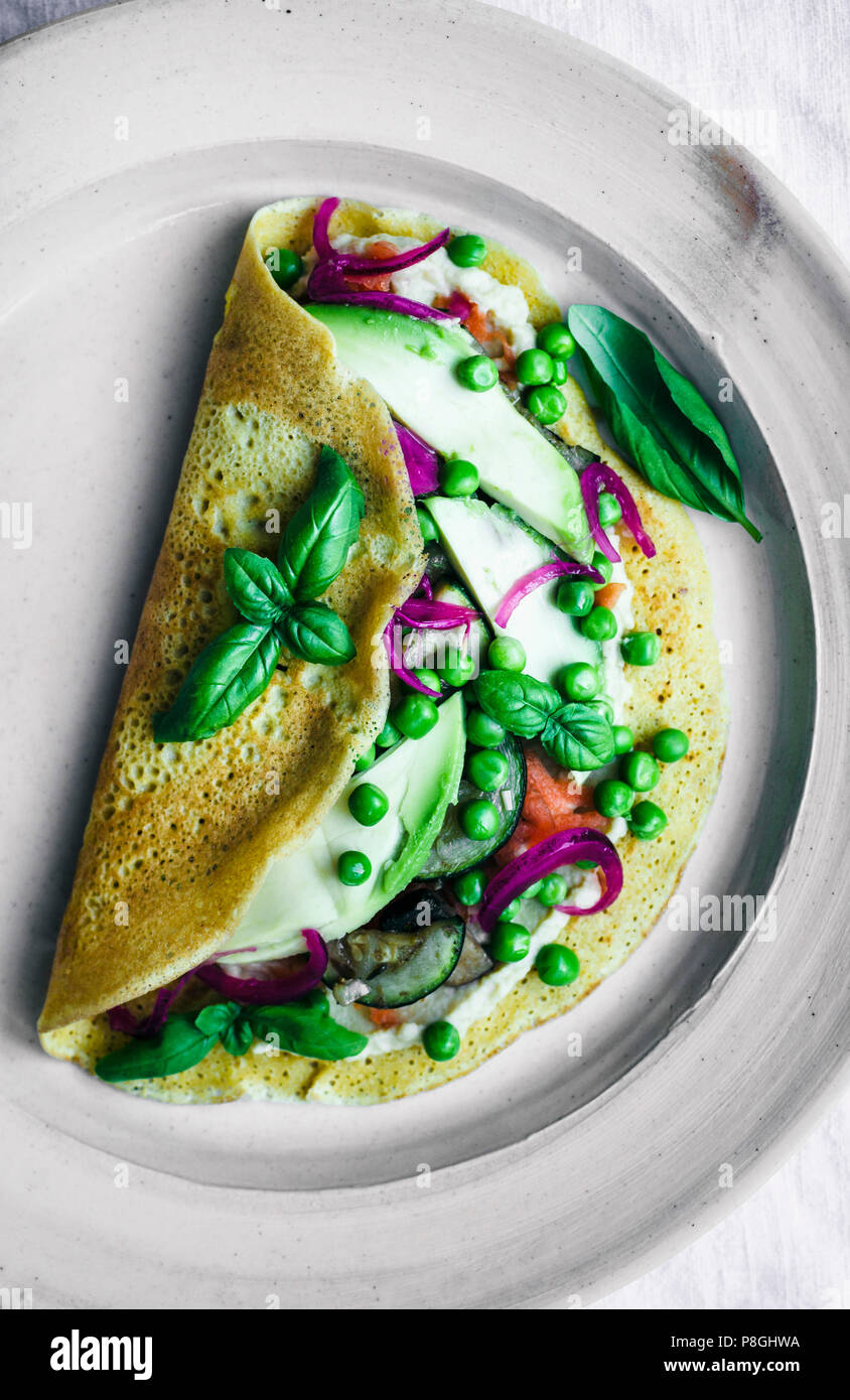 Crêpe farine de pois chiche avec de l'avocat, basilic, et les pois. Banque D'Images