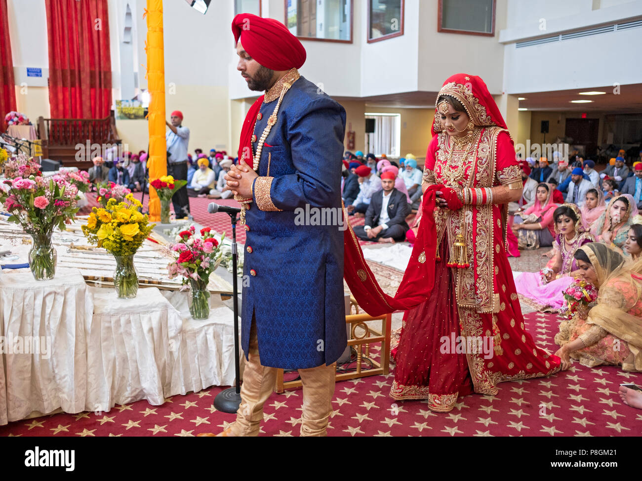 Une jeune mariée et se toilettent reliés par une écharpe rouge à leur cérémonie de mariage dans le temple à la Sikh Society à Richmond Hill, Queens, New York. Banque D'Images