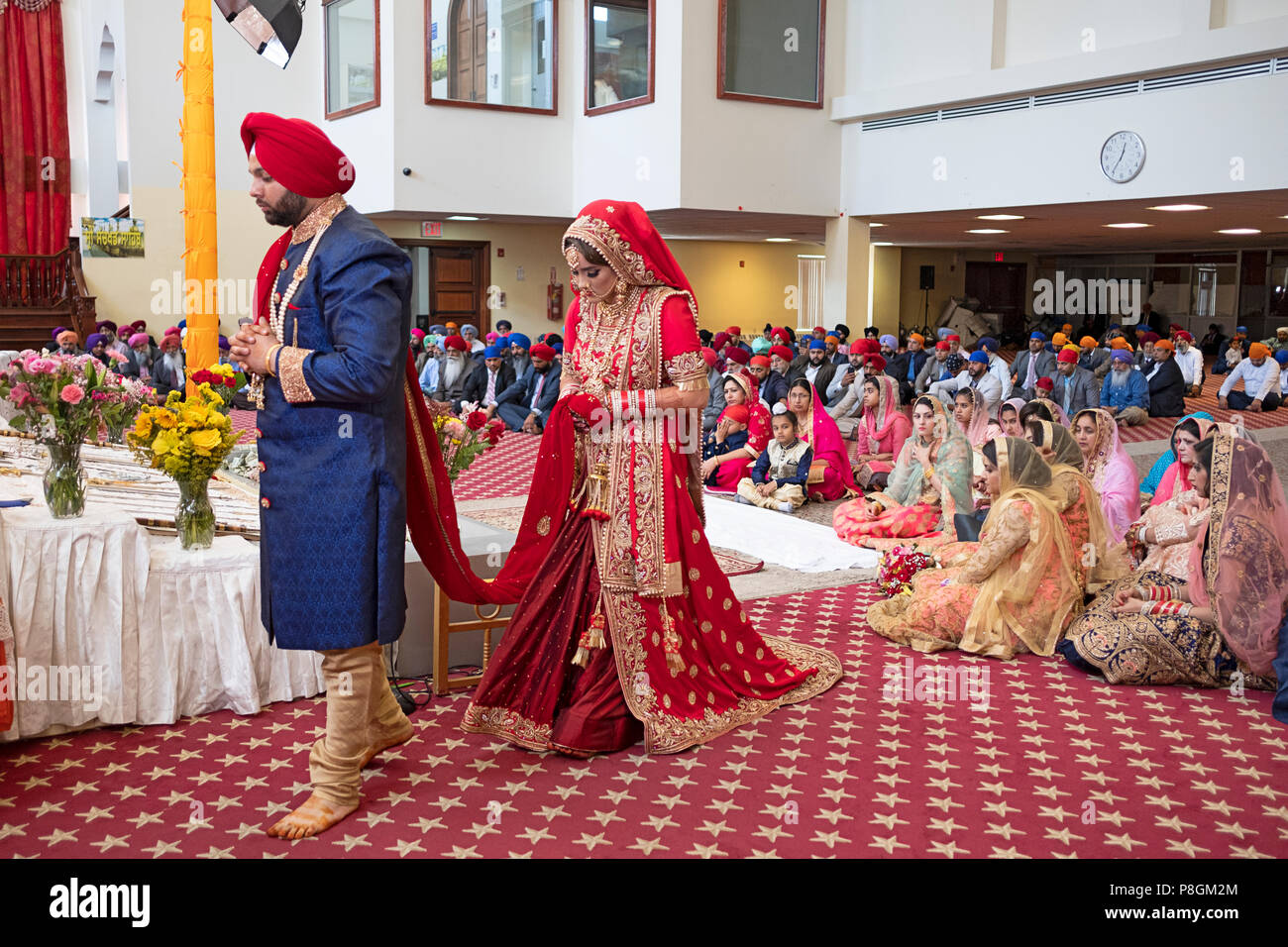 Une femme et un homme le cercle modifier au cours de leur cérémonie de mariage dans le temple à la Sikh Society à Richmond Hill, Queens, New York. Banque D'Images