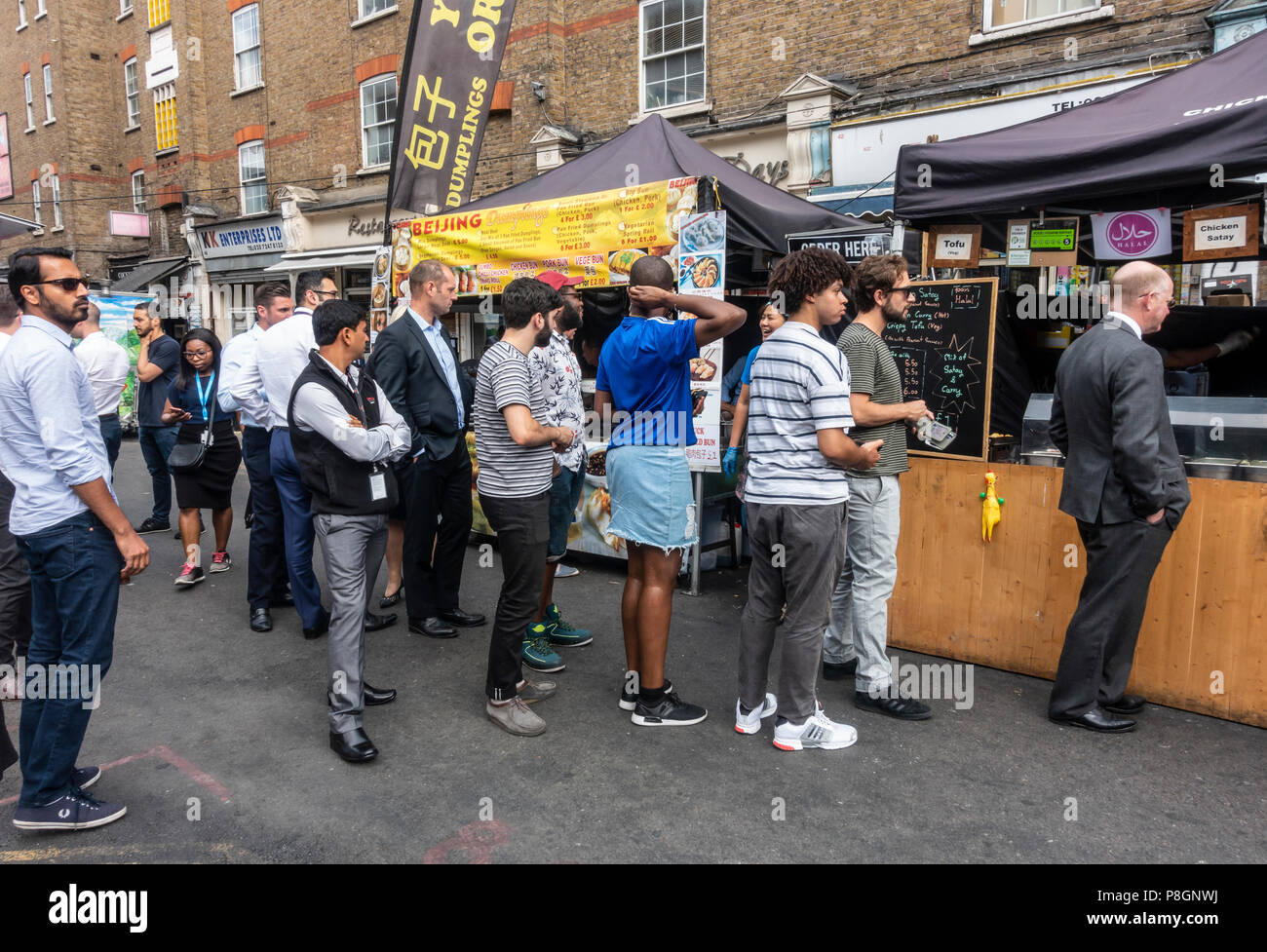 Les résidents locaux et les travailleurs en attente à deux stands de nourriture de rue dans le jupon Lane Market, Tower Hamlets, London, England, UK Banque D'Images