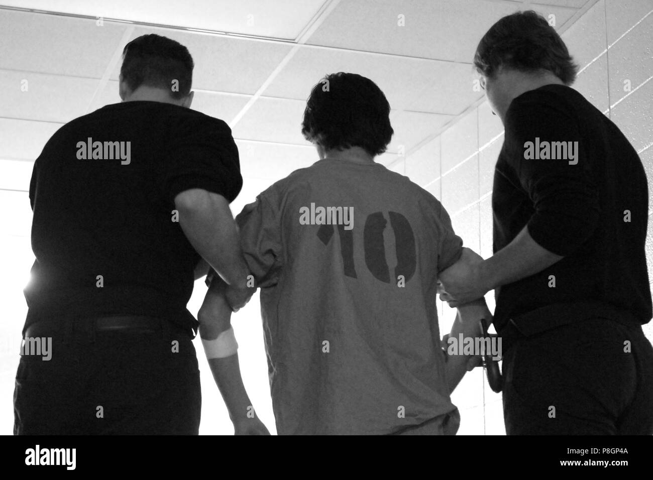 Un prisonnier dans une combinaison avec le nombre 10 est escorté par deux gardes. Banque D'Images