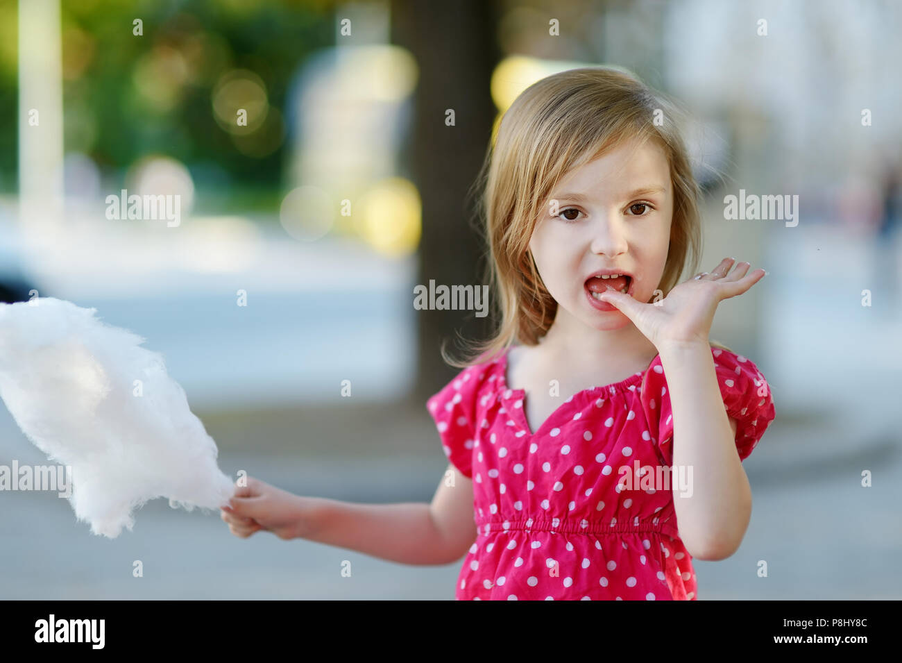 Adorable little girl eating candy-floss à l'extérieur à l'été Banque D'Images